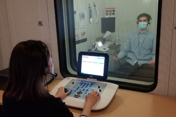 audiologists demonstrating use of audiometer in sound booth. Left to right: Gigi Cho and Charles Riendeau