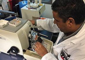 Fateh Beckhir, Medical Technologist, in the Cutting Station, where thin sections are cut from the wax block and placed on slides.