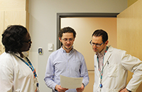 Denis discusses a case with his colleagues, Clinical Nurse Specialists Amélie Fosso and Octavien Boito