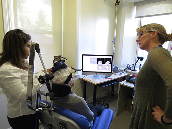 Dr. Koski and Dr. Sivakumaran performing the repetitive Transcranial Magnetic Stimulation (TMS) procedure with one of their study's participants. The procedure is non-invasive and totally harmless.