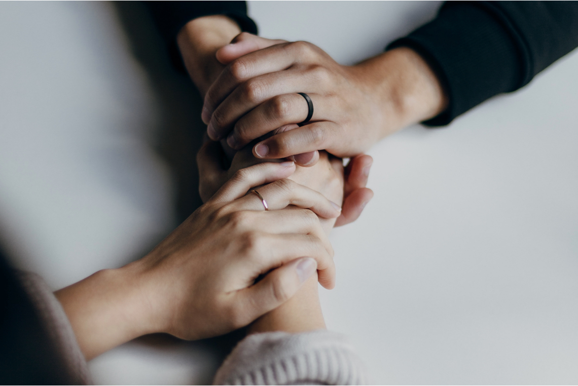 Four hands gently taking each others on a table