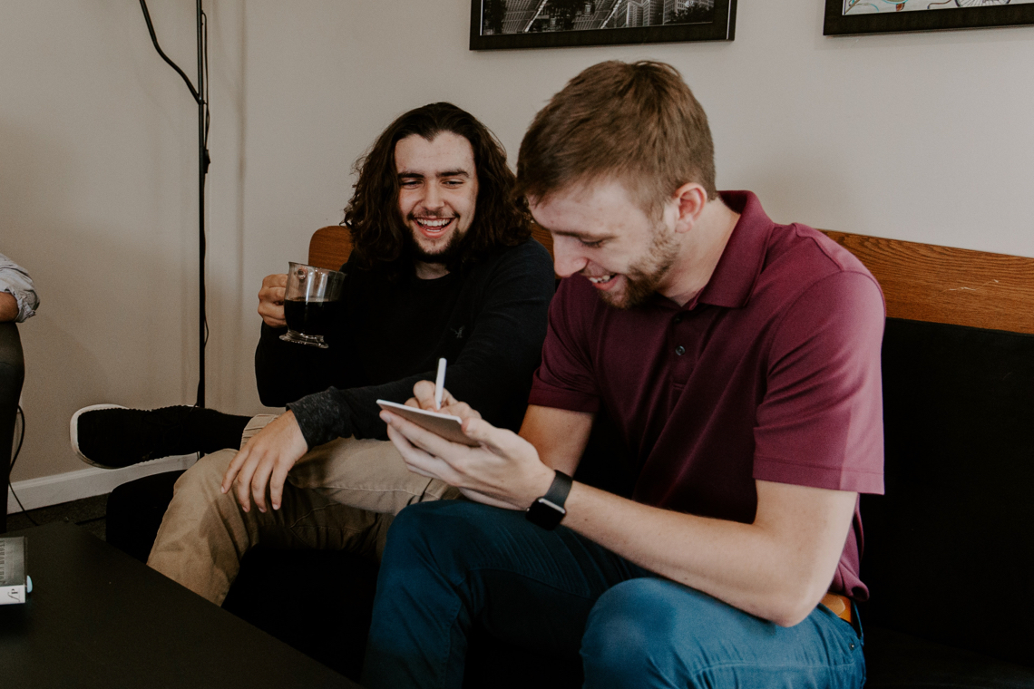 Two young men laughing while taking notes